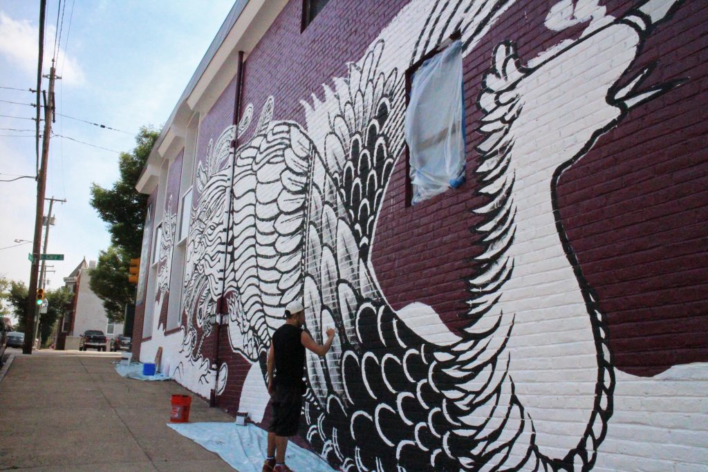 Moya paints a mural on ND&P's office downtown. Photos by Jonathan Spiers.