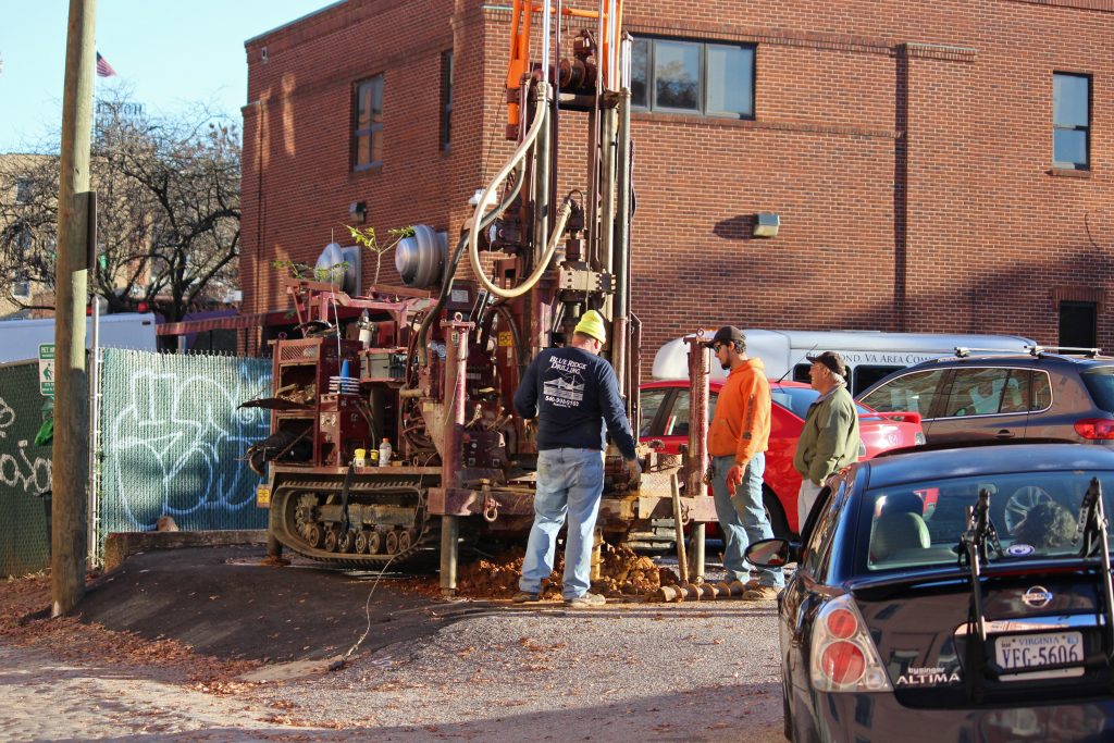 A drill bores down into a surface parking lot next to the Salvation Army at Grace and Foushee streets. Photo by Michael Thompson.