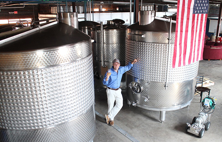 Buskey founder William Correll standing in the shadow of his new cider making tanks. 