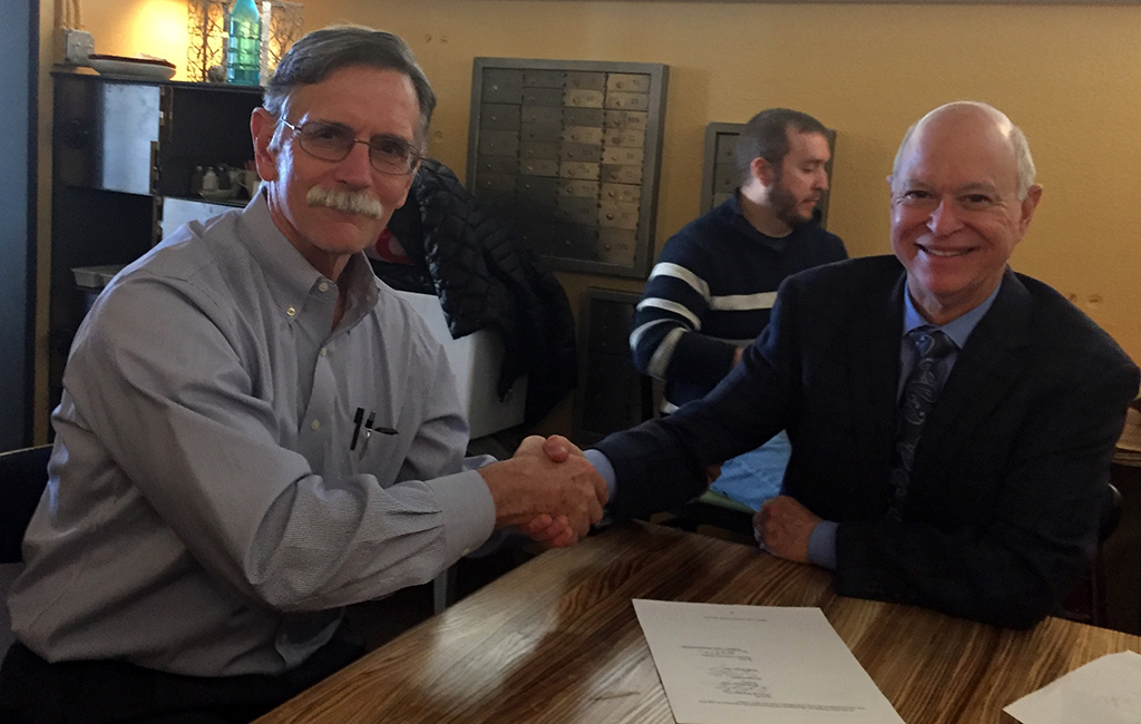 Mike Wicks, left, and Steve Biegler sign the merger deal. (Courtesy KWC)