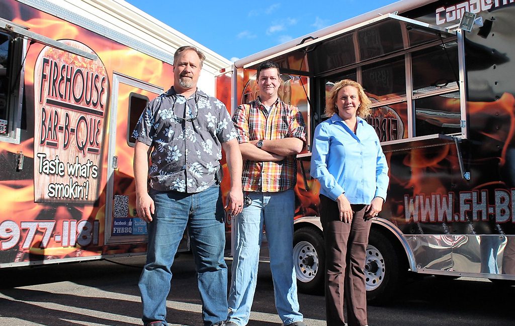 From left: Gordon Taylor, Andy Rayford and Lori Taylor in front of the Firehouse Bar-B-Que food trucks. (J. Elias O'Neal)