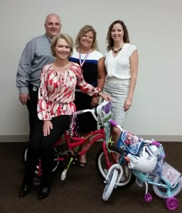 West Broad Village reps Kendall Rumsey, Tammy Philblad, and Melody Thomas present bikes to Virginia Homes for Boys and Girls President Claiborne Mason.